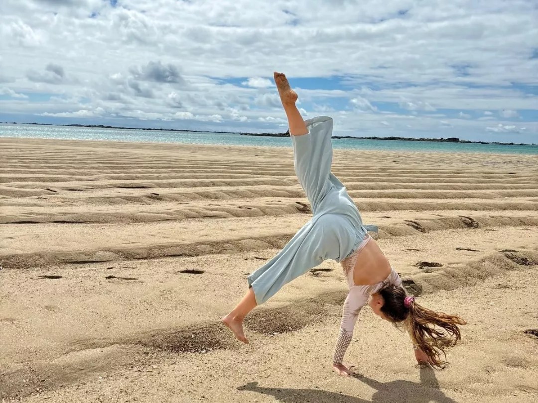 Dr Joanna Taylor doing a cartwheel on the beach, representing active lifestyle and wellbeing