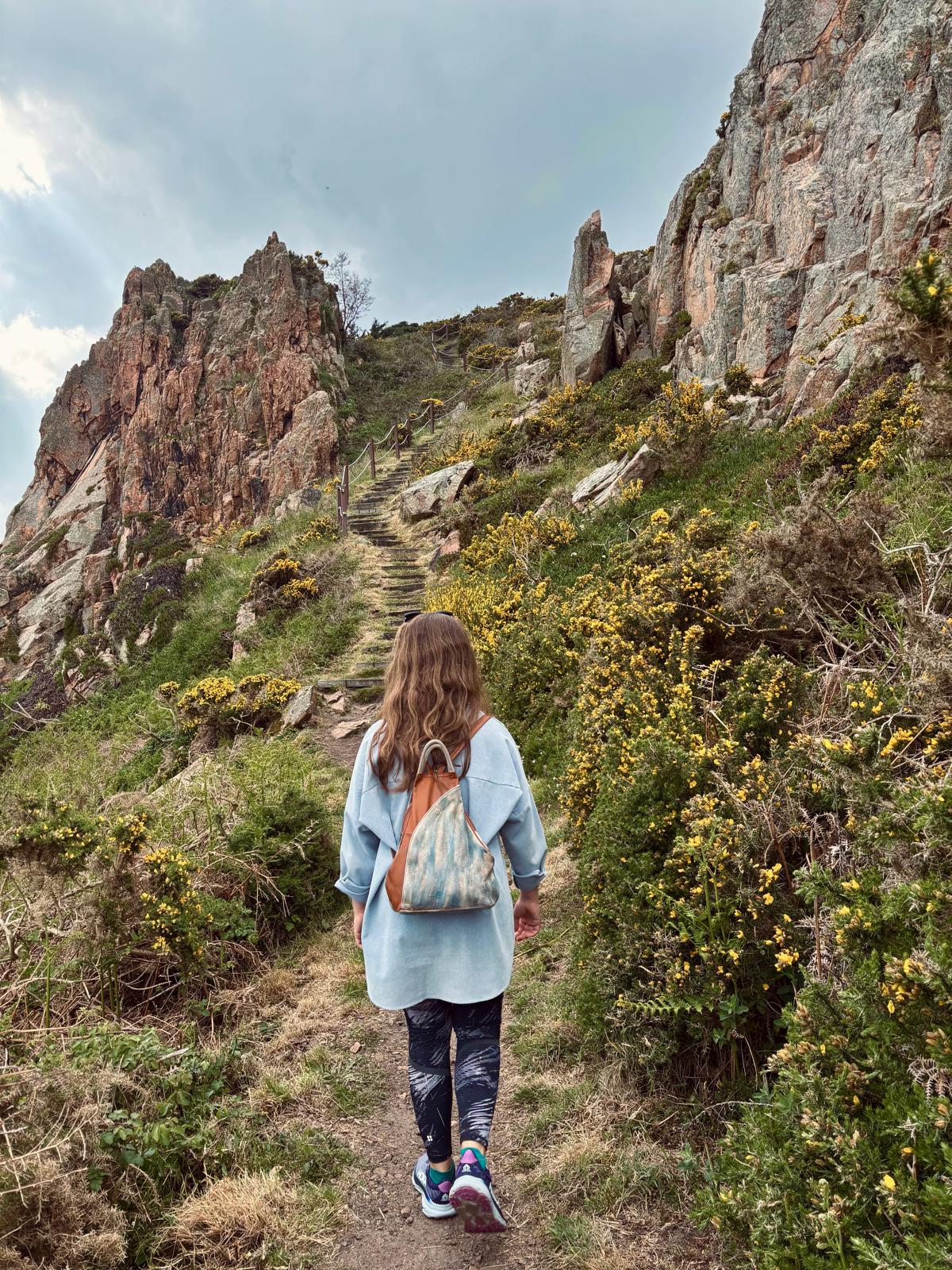 Woman walking along mountain steps, representing steady progress, resilience and a long-term approach to wellbeing