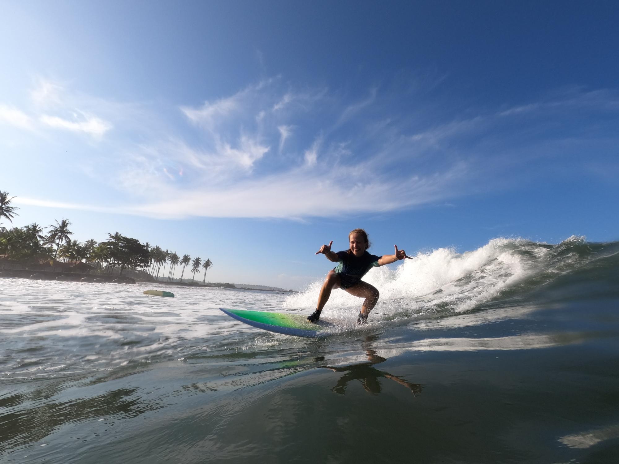 Dr Joanna Taylor surfing on the sea, representing balance, movement and wellbeing