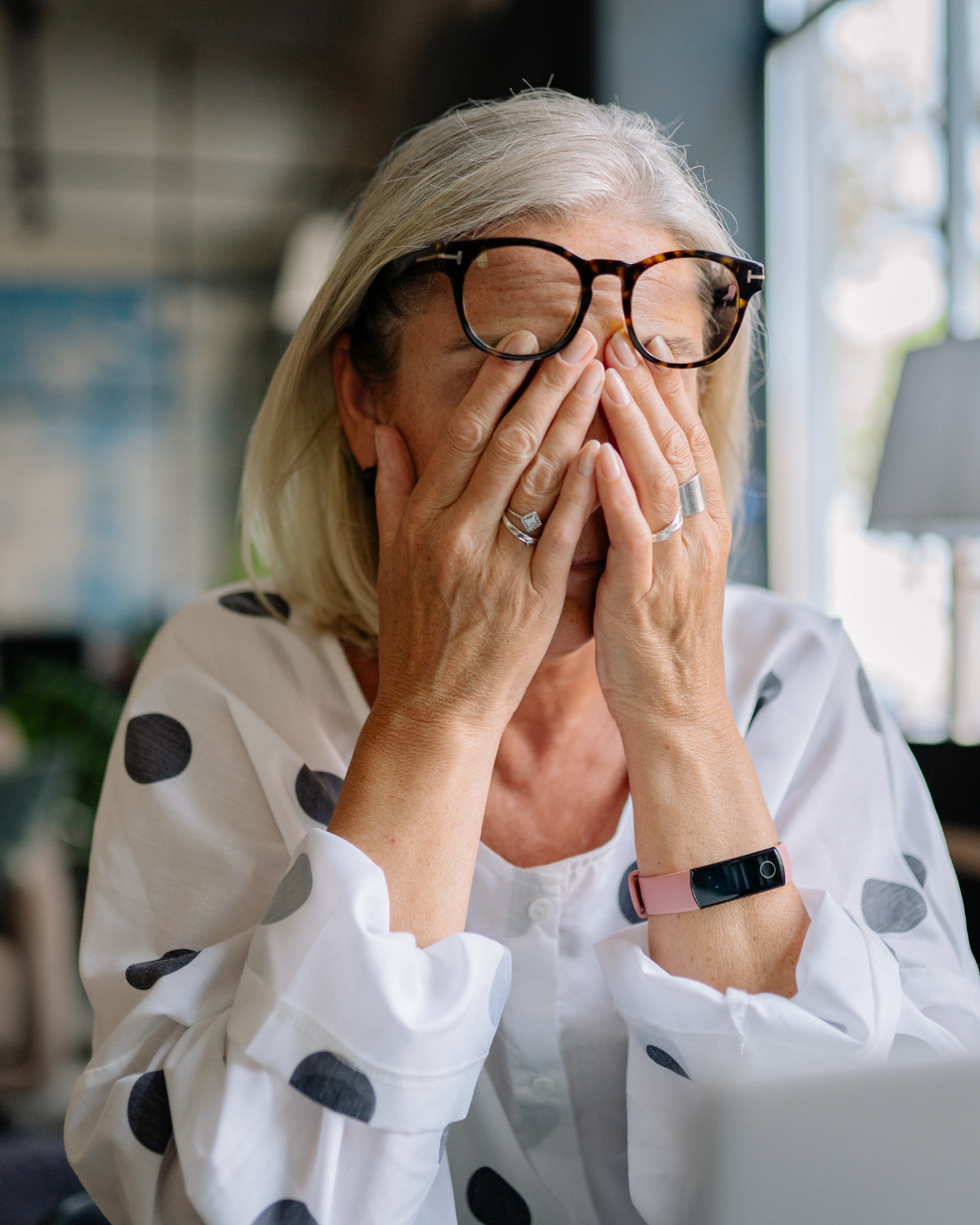 Woman covering her face showing stress and fatigue, representing mental wellbeing challenges