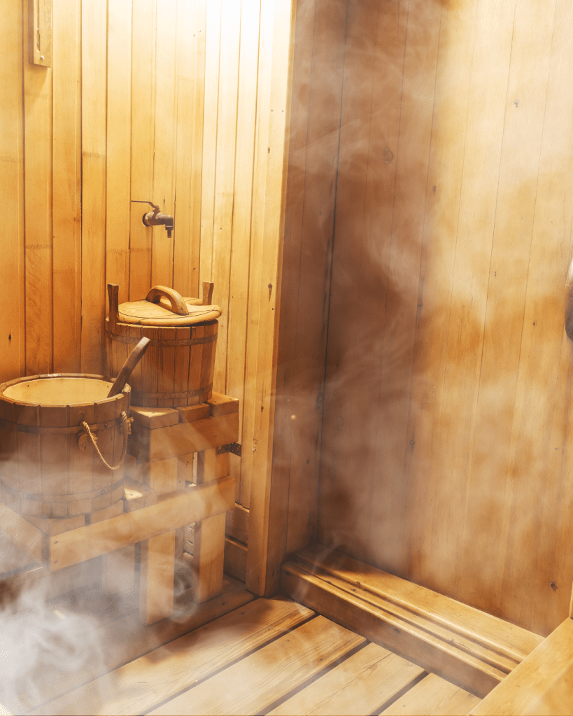 Interior of a wooden sauna with buckets and steam rising