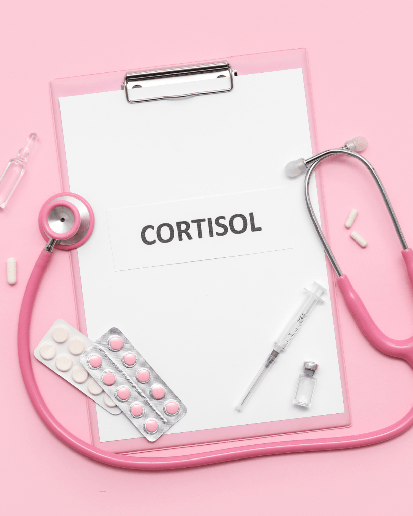 A pink clipboard with a white paper labeled 'CORTISOL', a pink stethoscope, various medications including tablets and capsules, a syringe, and a small vial, all displayed against a pink background.