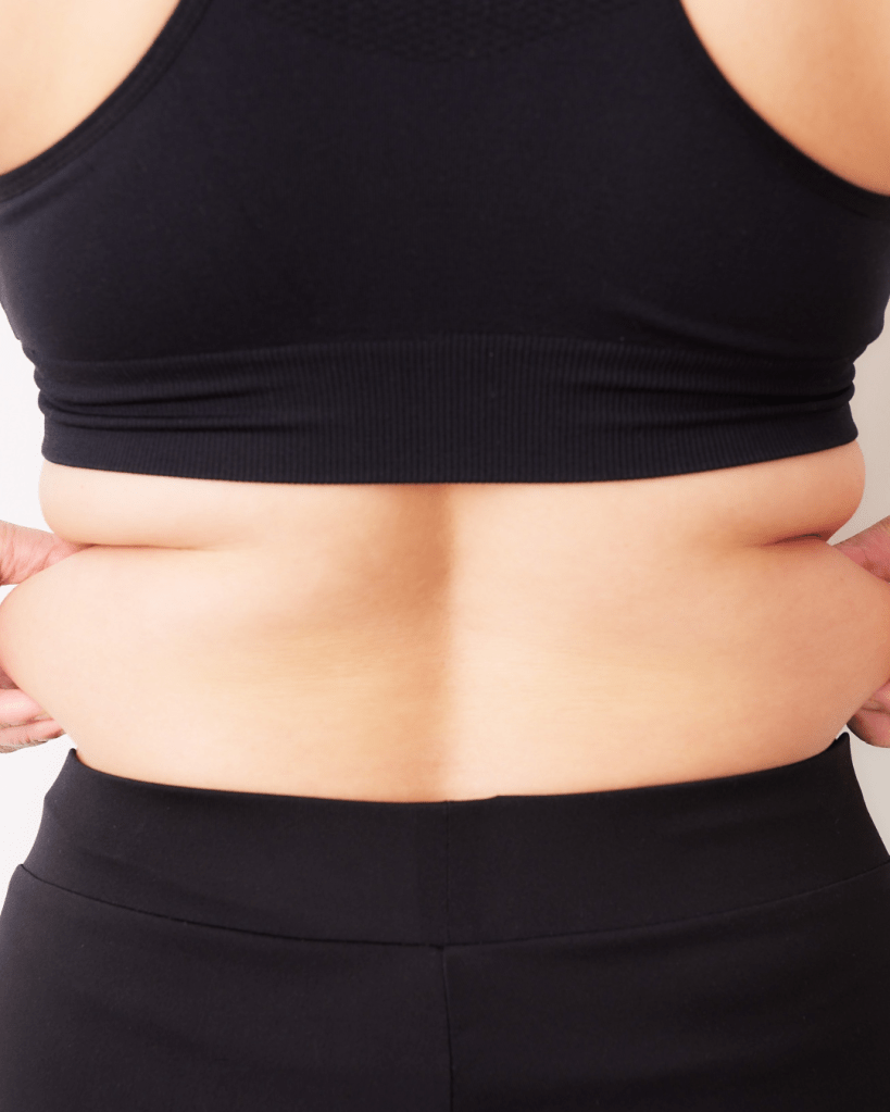 Close-up of a person's back wearing a black sports bra and black leggings, highlighting body contours and skin tone.