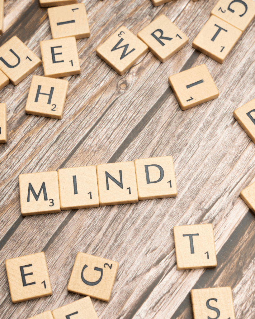 Scrabble tiles scattered on a wooden surface, with the word 'MIND' prominently displayed among other letters.