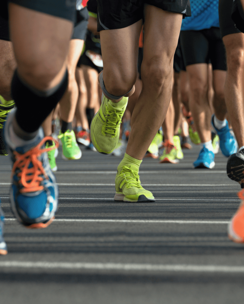 Close-up of runners' legs in motion during a race, showcasing various athletic shoes and colorful socks.
