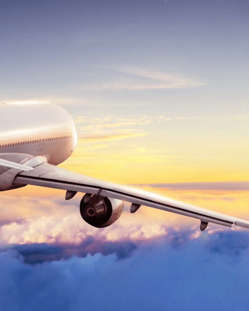 Close-up view of an airplane wing against a sunset sky with clouds.